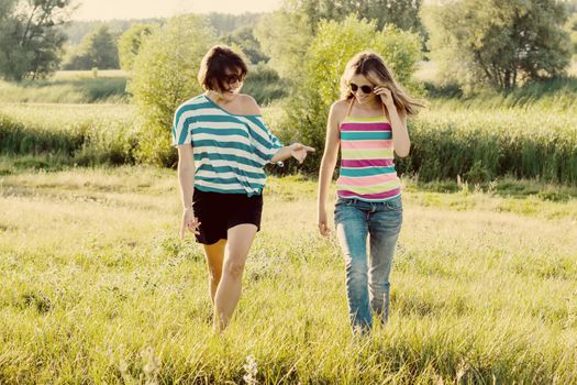 Woman with daughter teen walking in nature, Background green grass