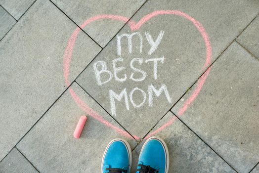 Mother's Day greeting card with handwritten text on the asphalt - my best mom heart and child feet