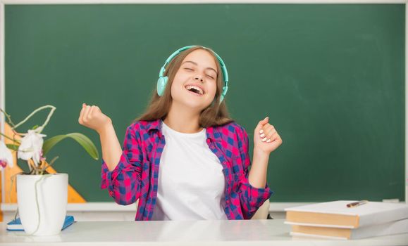 happy teen girl hold modern headphones in high school at blackboard, childhood.