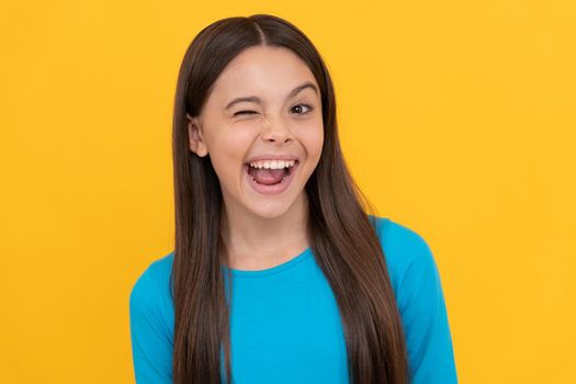 pretty look of young girl. face portrait of child on yellow background. express positive emotions. positive winking kid with long hair. beauty and fashion. female fashion model.