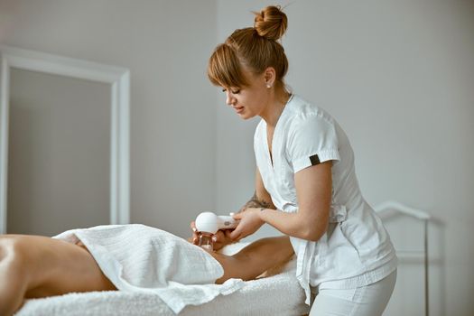 Confident female specialist is doing anticellulite leg massage to beautiful healthy caucasian female client