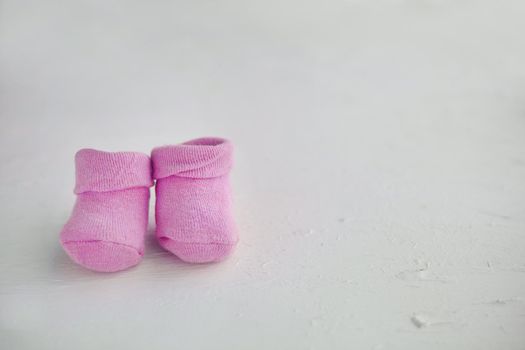 Pink baby socks on a textured rustic background with copy space. Newborn and pregnancy concept. Little girl socks