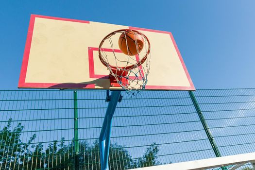 Street basketball, close-up of basketball ring and ball flying into the basket