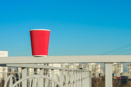 Red paper cup, background modern city and blue sky, copy space.