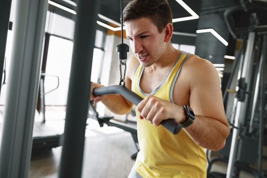 Young bodybuilder doing heavy weight exercise for biceps in a gym, close up