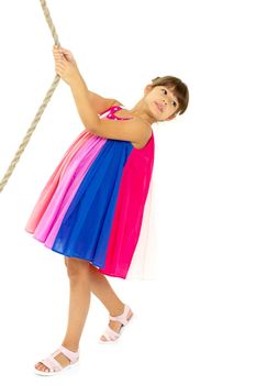 Adorable girl playing with rope. Cute girl posing against white background and looking at camera. Full length shot of happy child in bright sundress and sandals having fun on playground