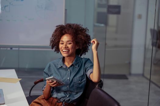 Happy multiethnic businesswoman working in the office while holding smartphone. Business, employment concept