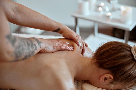 Professional confident massage master is doing procedures to caucasian woman in minimalistic modern cabinet