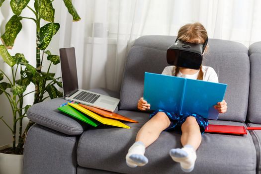 Trying new technologies. Little schoolgirl wearing big VR glasses being impressed playing virtual games. Home school, online education, home education, quarantine concept - Image