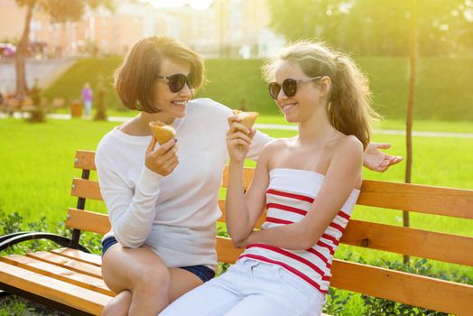 Mom and daughter laugh, eat ice cream and enjoy socializing.