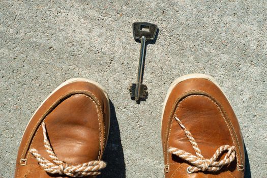 Key on the asphalt and female feet. Abstract image of woman found, lost key.