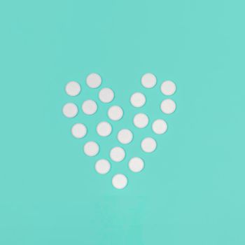 Medical background with pills. World Heart Day concept. Medical background. White Pills in form of heart on blue background. Flat lay. Heart health concept.