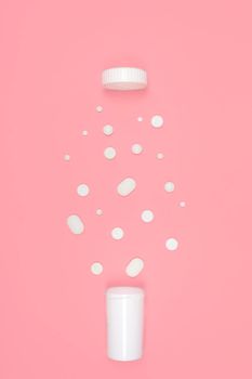 Medical background with pills. White pills pour out of a bottle on a pink background. Flat lay concept.