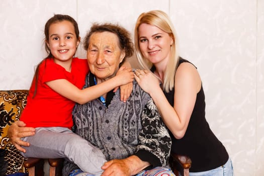 Senior woman hugging granddaughter while sitting on sofa at home