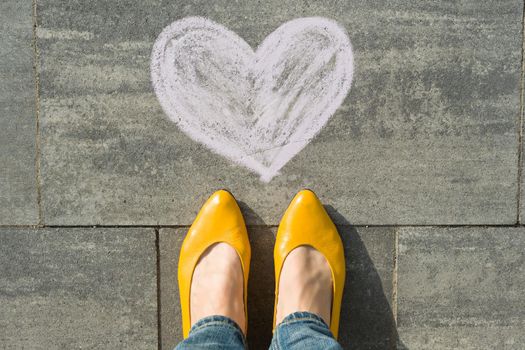 Female feet with symbol heart painted on the asphalt.