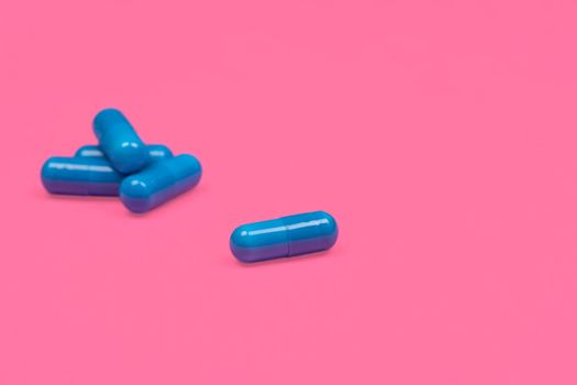 Medical background. Blue capsule pill on pink background. Blue capsules pill spread on fuchsia or pink background with copy space. Macro photo