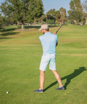 professional sport outdoor. back view. male golf player on professional golf course. portrait of golfer in cap with golf club. people lifestyle. man playing game on green grass. summer activity.