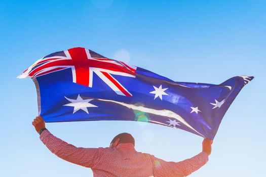 Man with a flag of Australia standing in morning field