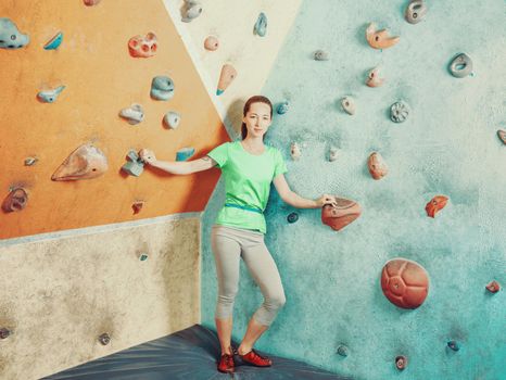 Sporty young woman standing in climbing gym, looking at camera.