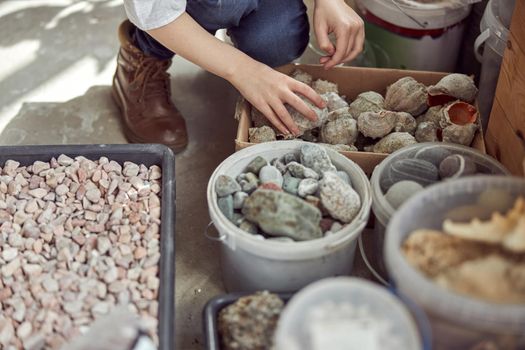 Hands of young caucasian girl who is working to do a composition.Flourist shop with different kinds of dryed flowers