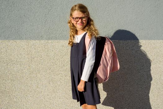 Outdoor portrait of an elementary school student in uniform with schoolbag.