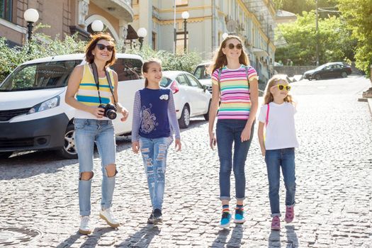 Woman with a group of children is laughing, walking around the city. Background of the European city, summer weekend, vacation, tourism.