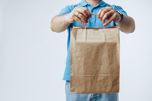Unrecognizable man in blue polo shirt with food delivery orders against light grey background