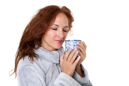 Smiling woman holding porcelain mug. Cheerful brown haired woman posing with cup of coffee or tea in her hands against white background. Female person enjoying of hot drink in the morning