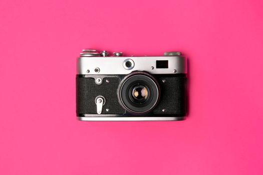 Retro camera isolated on bright pink background. Pop art concept. Flat lay in minimal style