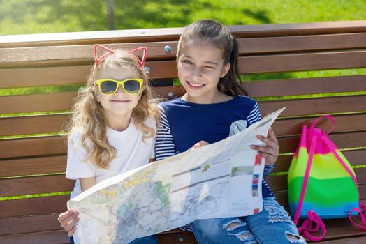 Outdoors portrait children tourists. With map of city on the bench.