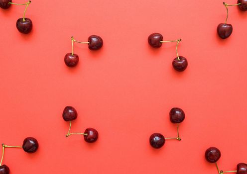 Big sweet cherry on a bright coral background. Cherries close up. Summer flat lay berry background. Top view cherry pattern.