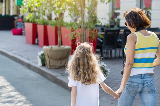 Urban portrait of mother and child daughter. Back view.