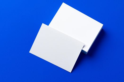 Blank white businesscards on classic blue background, copy space