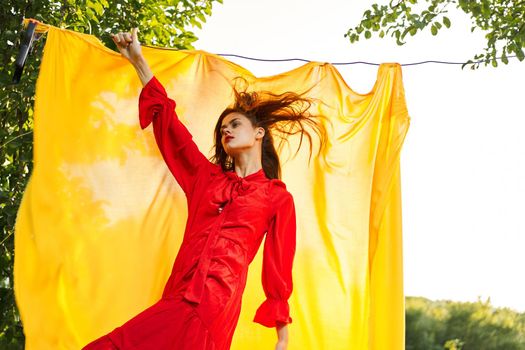 beautiful woman posing in red dress outdoors yellow cloth. High quality photo