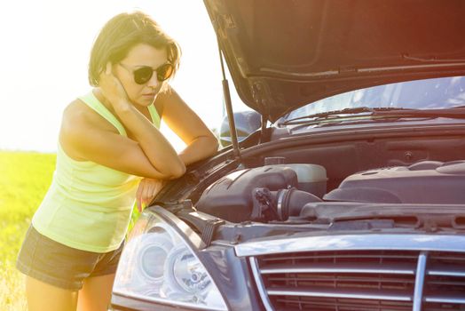 Frustrated woman driver near a broken car. Machine on a country road. The woman has stress