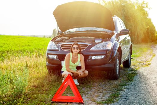 Frustrated woman driver near a broken car. Machine on a country road. The woman has stress