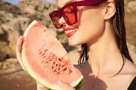 cheerful woman in sunglasses and watermelon nature rocks. High quality photo