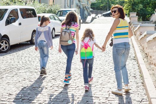 Woman with a group of children is laughing, walking around the city. Background of the European city, summer weekend, vacation, tourism.
