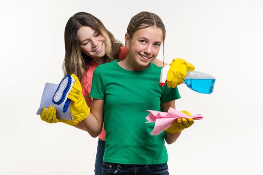 Cleaning, domestic duties and teamwork concept. Two teenage sisters wearing yellow protective gloves and holding them for cleaning