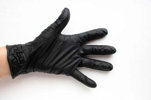 Hand in a black surgical medical glove, isolated on a white background. Production of rubber protective gloves.Hygiene and sanitary standards.