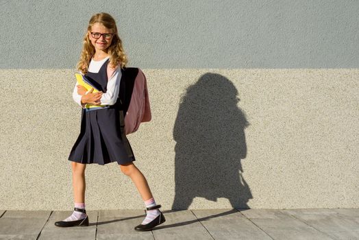 A schoolgirl of elementary school with notebooks in his hand. A girl with a backpack goes to school. Back to school