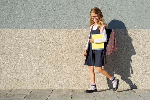 A schoolgirl of elementary school with notebooks in his hand. A girl with a backpack goes to school. Back to school!