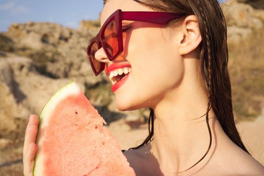 cheerful woman in sunglasses and watermelon nature rocks. High quality photo