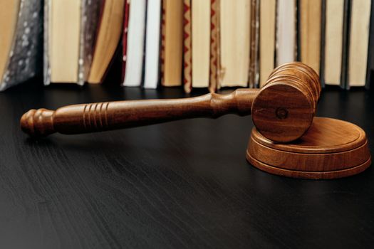 Judge's gavel on wooden table in dark. Close up.