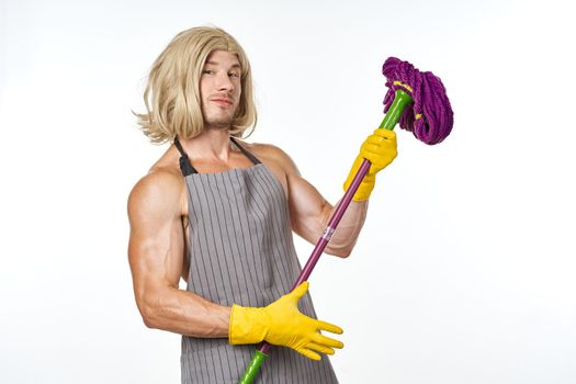 muscular man in apron with a mop in a woman's wig. High quality photo