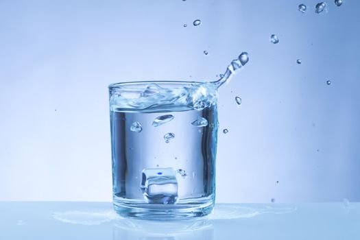 ice cube falling into a glass of water