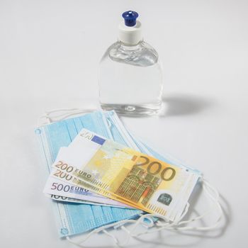 Alcohol gel hand sanitizer and disposable hygienic mask and euro banknotes on gray background