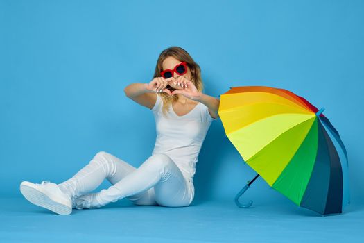 fashionable woman with umbrella rainbow colors posing blue background. High quality photo