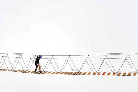 Man crossing rope bridge over the abyss in foggy mountains in Russia