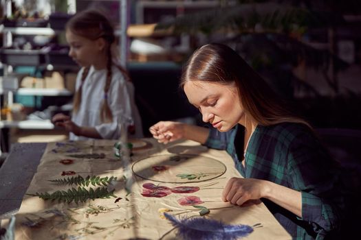 Flourist shop with different kinds of dryed flowers. Young happy confident specialist is working with her female kid.